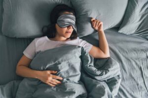 Woman sleep in eye patch in grey bed. copy space